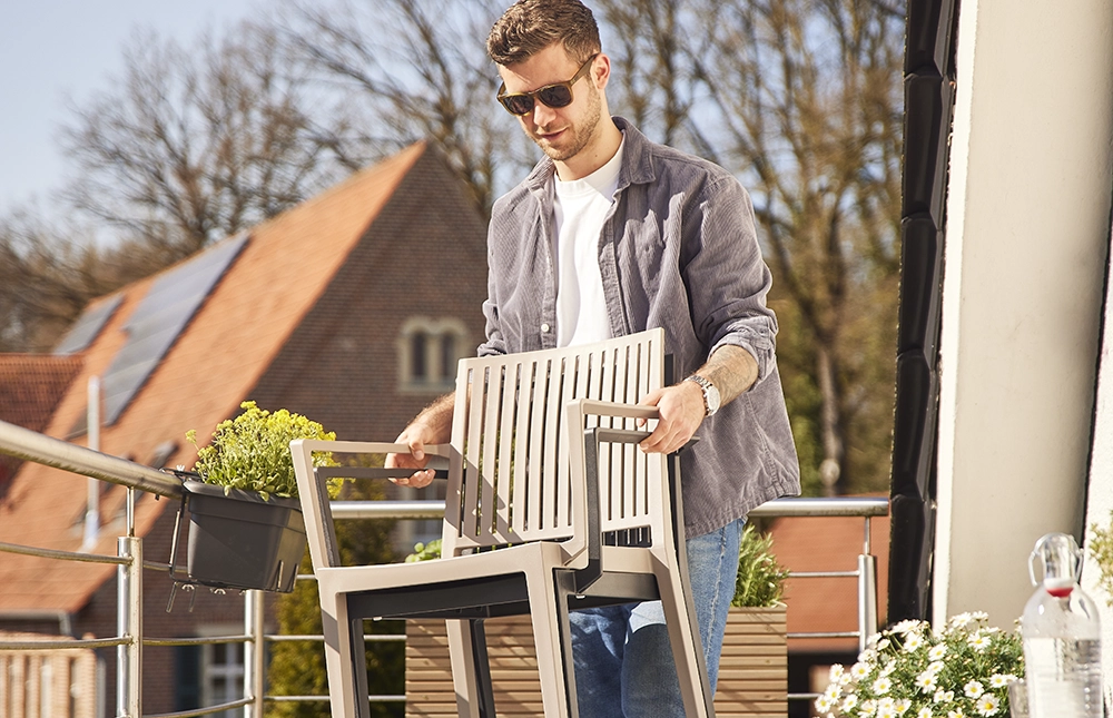 Ein Mann trägt gestapelte Stühle auf dem Balkon