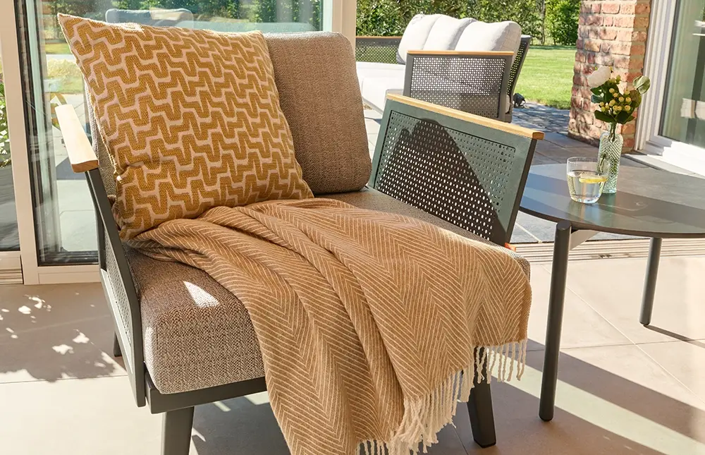 Ein gemustertes Kissen und eine Decke liegen auf einem Stuhl